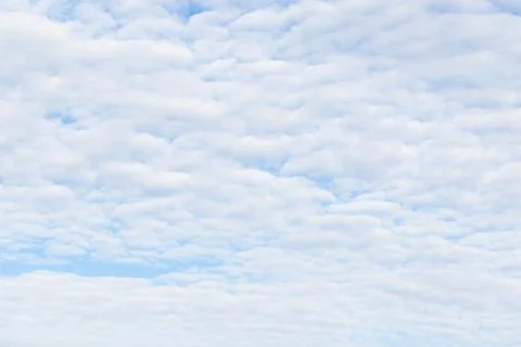 Soft altocumulus clouds stretch across a pale blue sky Foto stock