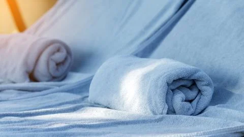 Soft and clean rolled bath towels on daybed by swimming pool Stock Photos