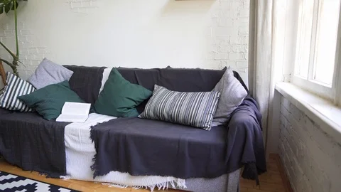 Soft beautiful cosy sofa with a book, pillows, plaid and blanket. Lagom concept Stock Footage 114565577