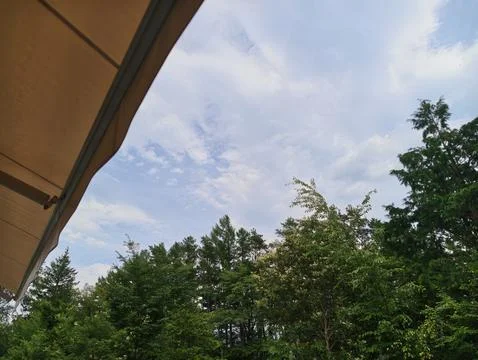 Soft beige awning frames a sky filled with wispy clouds Stock Photos