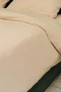 Soft beige bedding set on a modern bed with pillows and blanket 库存照片