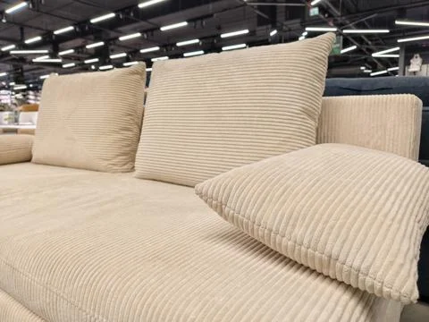 Soft beige sofa with three throw pillows, available for purchase in a furni.. Foto stock