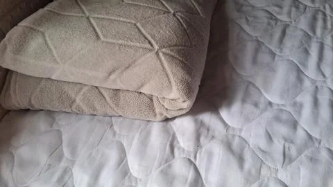 Soft beige textured blanket folded neatly on a white mattress Stock Photos