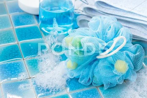 Soft blue bath puff or sponge on blue tile background Stock Photos