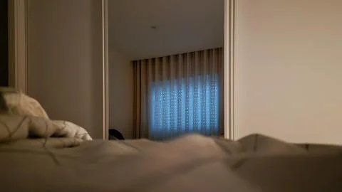 Soft blue light from a window is reflected in a bedroom mirror Stock Photos