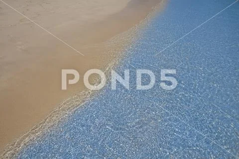 Soft blue ocean wave on sandy beach. Background. Stock Photos