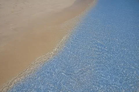 Soft blue ocean wave on sandy beach. Background. Stock Photos