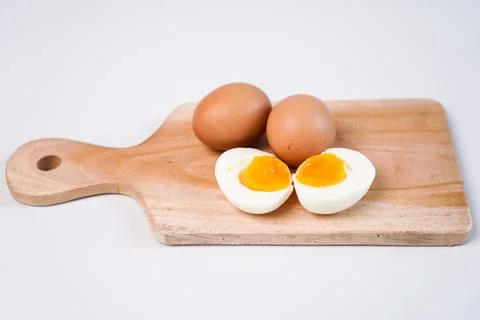 A soft boiled egg cut into two halves in the foreground with two whole brow.. Stock Photos