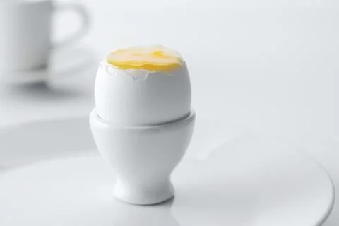 Soft boiled egg in egg cup on white background, plate and cup. Stock Photos