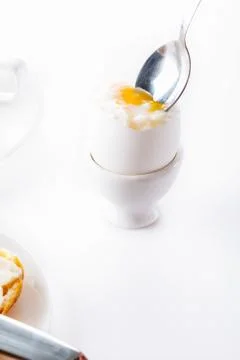 Soft boiled egg in egg cup on white background, plate and cup. Close up. Sele 스톡 사진