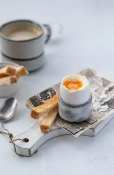 Soft-boiled egg in an eggcup with toasts and coffee on the wooden background Stock Photos