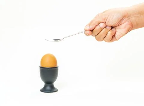 Soft-boiled egg with Hand and spoon. Stock Photos