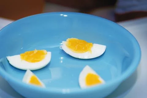 Soft-boiled egg, quartered vertically, served on a blue plastic plate for a.. Stock Photos