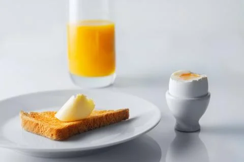 Soft boiled egg, toasted bread, butter and glass of orange juice. Selective f 스톡 사진