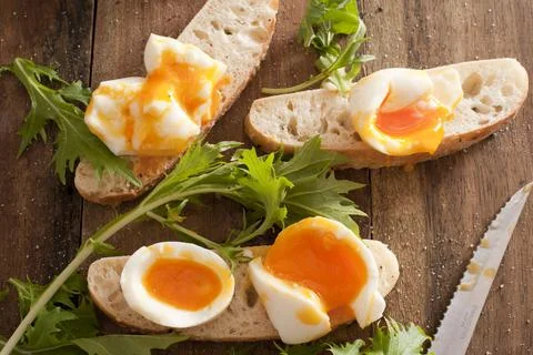 Soft boiled eggs broken open on baguettes Stock Photos