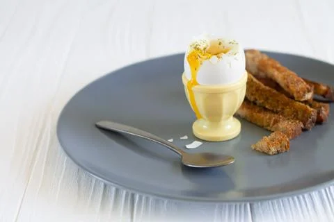Soft boiled runny egg in an eggcup with toasted bread for breakfast Stock Photos