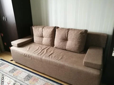 A soft caramel-colored sofa stands in the room between dark cabinets Stock Photos
