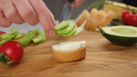 Soft cheese with avocado, tomato on piece of baguette bread Stock Footage 262048687