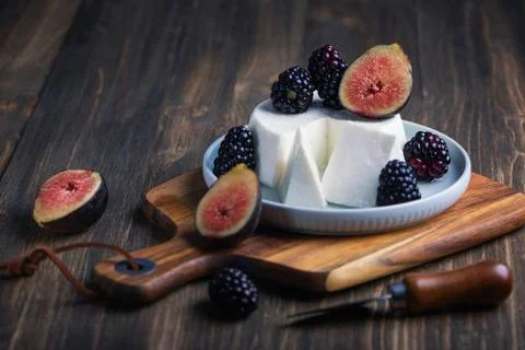 Soft cheese with brambles and fig halfs on a wooden rustic board. Close up da Foto stock