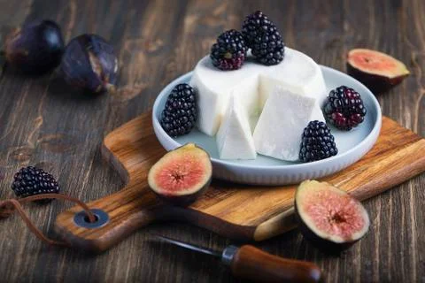 Soft cheese with brambles and fig halfs on a wooden rustic board. Close up da Stock Photos