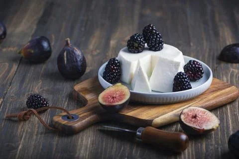 Soft cheese with brambles and fig halfs on a wooden rustic board. Close up da Foto stock