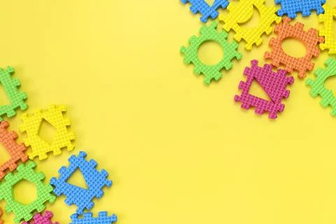 Soft children's multi-colored jigsaw puzzles on yellow background flat lay Stock Photos