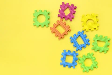 Soft children's multi-colored jigsaw puzzles on yellow background flat lay Stock Photos