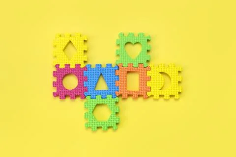 Soft children's multi-colored jigsaw puzzles on yellow background flat lay Stock Photos