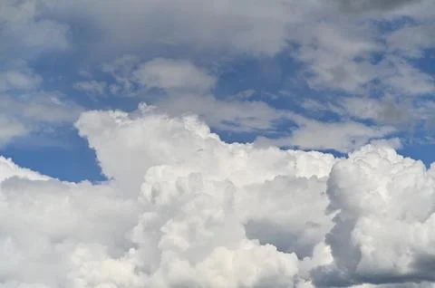 Soft cloud clusters float across clear azure sky. Stock Photos