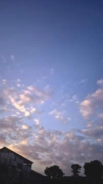 Soft clouds blush at dusk, silhouetted against deepening blue Stock Photos