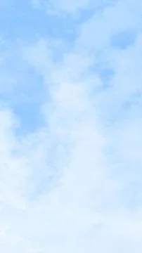 Soft clouds drift gently across a serene, pale blue sky 库存插图