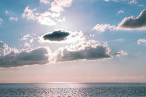 Soft clouds over the sea with sun rays through the sky Stock Photos