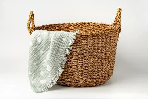 Soft cotton blanket in a straw basket on white background Stock Photos
