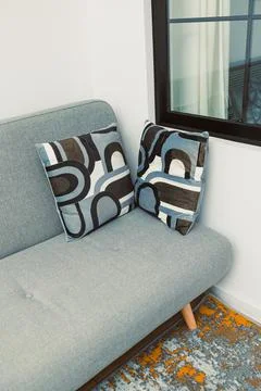 Soft couch with patterned pillows in a bright room near a window during dayti Stock Photos