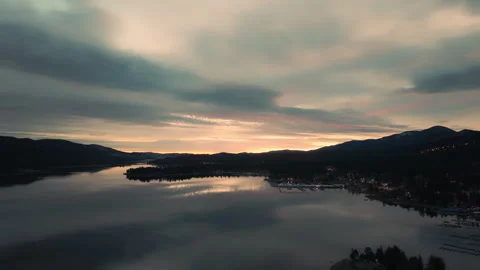 Soft dawn light over lake with pastel sky and still water reflecting forest Vidéo 328899016