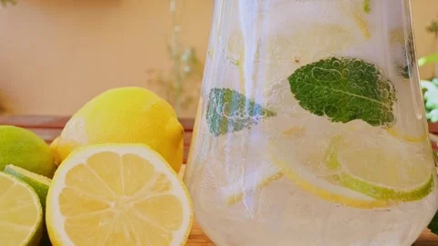 Soft Drink with Ice, Bubbles, Mint, lemon, lime in a glass decanter. Outdoors Stock Footage 274665932