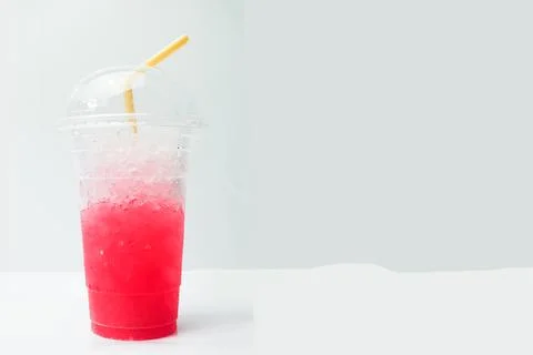 Soft drink with ice in plastic glass on white table. Selective focus Stock Photos