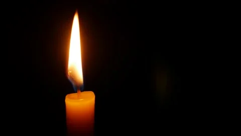 A soft flame lifts through open darkness as gentle flicker embodies longing Stock Footage 325034937