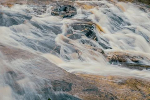 Soft flowing waterfall over dark rock formation in natural forest stream. L.. 库存照片