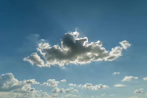 Soft, fluffy clouds drift gracefully through the sky, illuminated by the warm Stock Photos