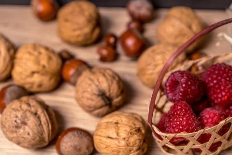 Soft focus, blurring background. Hazelnuts and walnuts. Raspberry wicker basket Stock Photos
