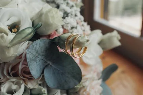 Soft focus captures wedding rings resting on a bouquet Stockfoto's
