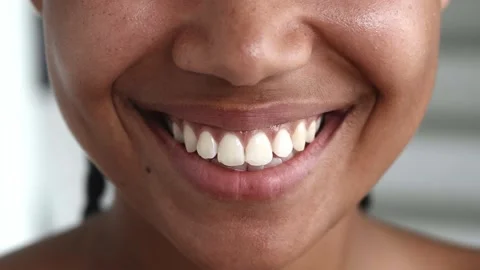 Soft focus on the glossy lips of a charming young woman spreading into a Stock Footage 202060711