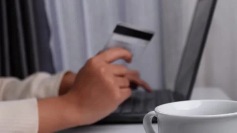 Soft focus hand holding a card while typing on keyboard Stock Footage 274043357