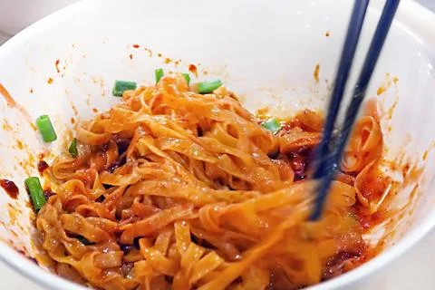 Soft focus movement blurred of use chopstick mixing egg flat noodle with chil Foto stock