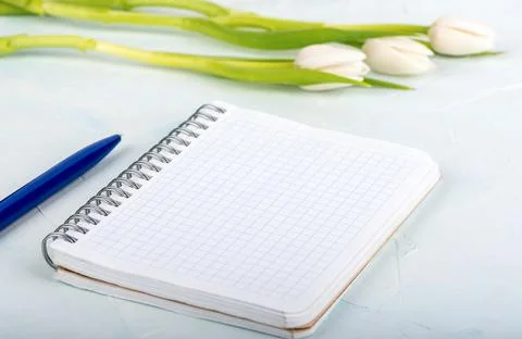 Soft focus notepad with checkered sheets and blurred tulips in the background Stock Photos