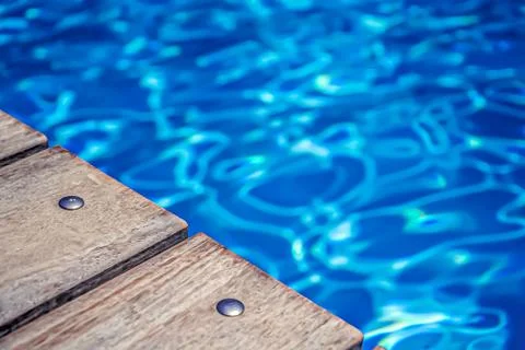 Soft focus. Open swimming pool bord, water and natural wood texture. Stock Photos