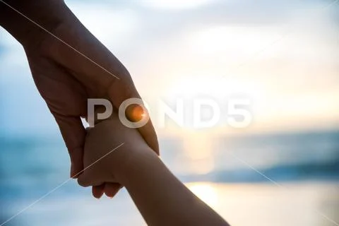 Soft focus parent hold the little child hand during sunset, warm tone. Stock Photos