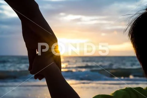 Soft focus parent hold the little child hand during sunset, warm tone. Stock Photos