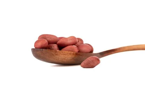 Soft focus on peeled peanuts on a spoon and on a white background. Stock Photos